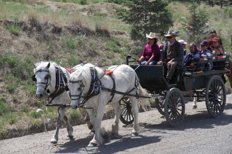 horse drawn wagon with people sitting on it.