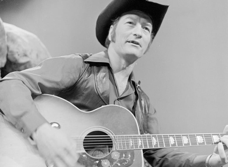 A black and white image of a man holding a guitar.