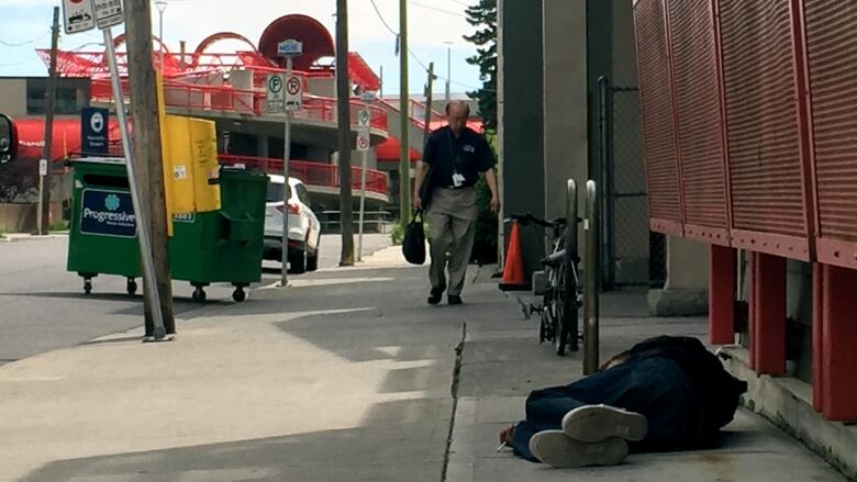 A man lays in the shade of a building in downtown Calgary.