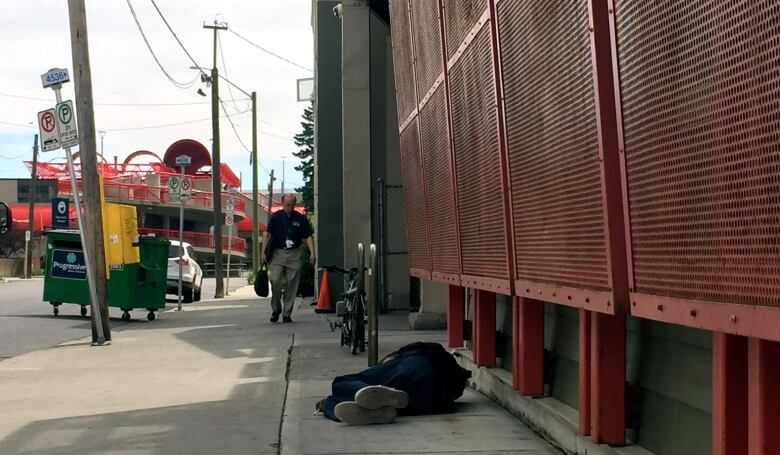 A man lays in the shade of a building in downtown Calgary.