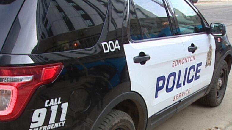 A black and white police car is on the road.