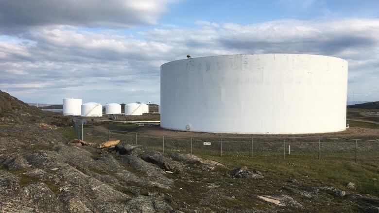 Large white fuel tanks sit just outside of Iqaluit on the green tundra in this photo. 