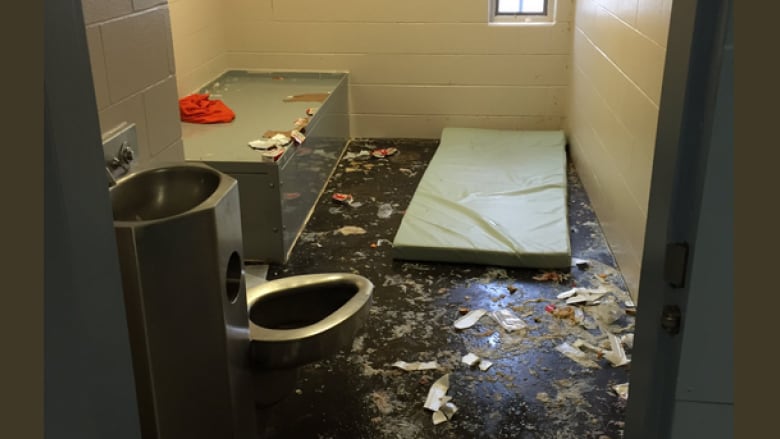 A segregation cell, with what appears to be a mat and debris on the ground.