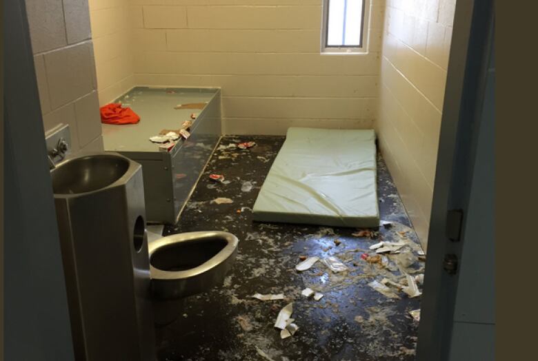 A segregation cell, with what appears to be a mat and debris on the ground.