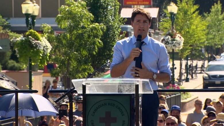 Trudeau stands at a podium speaking. 