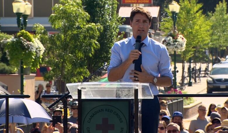 Trudeau stands at a podium speaking. 