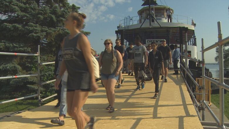 People walk off the front of a docked ferry.