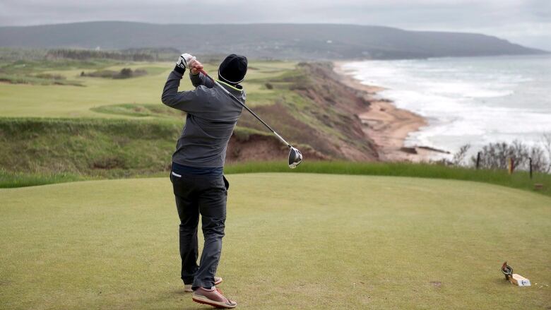 A man finishing a golf swing on a course