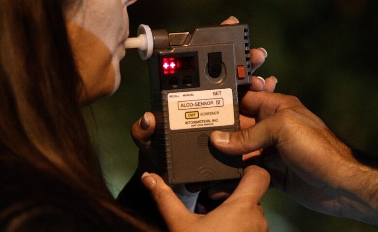 a woman blows into a blood alcohol censor