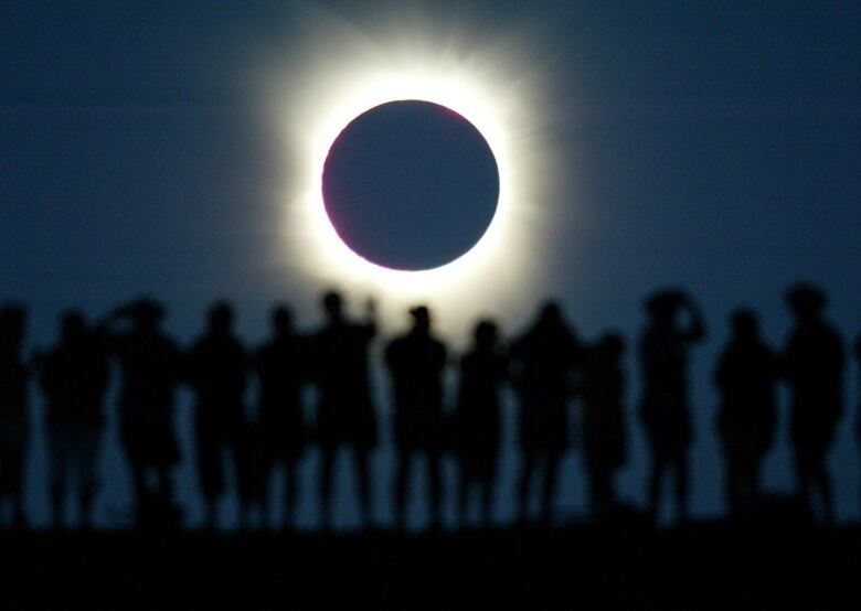 Tourists watch the sun being blocked by the moon during a solar eclipse in the Australian outback town of Lyndhurst, located around 700 kilometres (437 miles) north of Adelaide December 4, 2002. The town is one of only four in Australia where the 26 second-long full eclipse of the sun could be seen and occurred during celebrations for the Year of the Outback. The shadow path of whats called totality, where the 'diamond ring' effect becomes visible, can be seen on a path that is just 36 kilometres wide. REUTERS/David Gray 