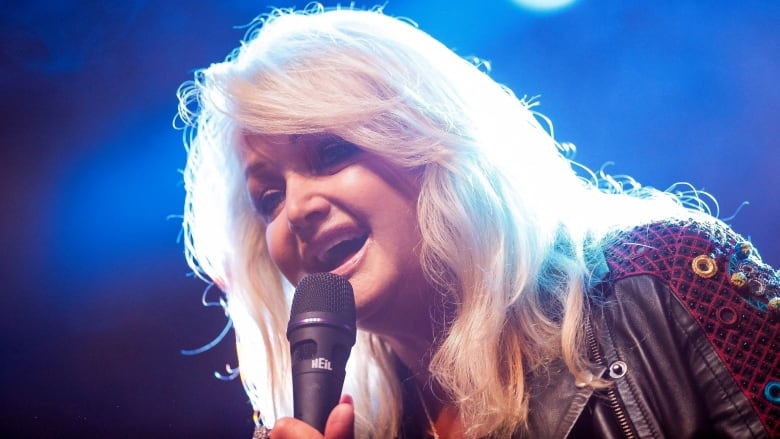 Woman with blonde hair holding a microphone