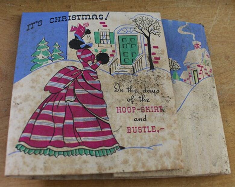 A Christmas card shows a woman in an old-fashioned dress and says 