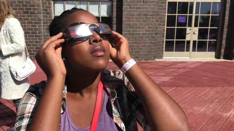 Someone uses eclipse glasses to look at the sky.