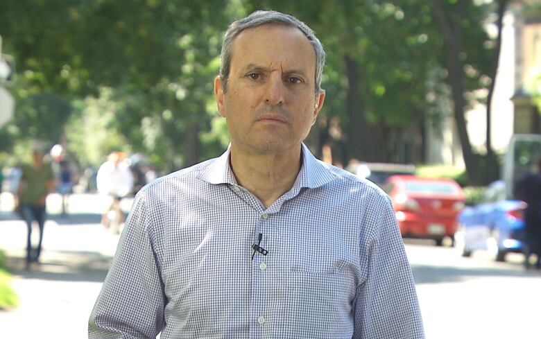 Man in striped white and blue shirts standing outside.