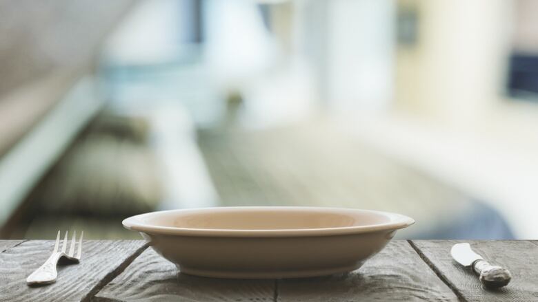 A bowl on a wooden table flanked by a fork and knife.