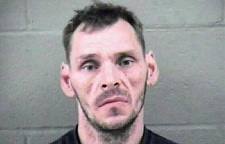 An earlier photo of Schoenborn from around the time of the child killings shows a man with a blank look and light beard standing in front of a grey wall.