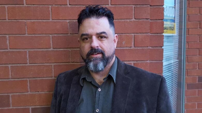 A man standing in front of a brick wall.