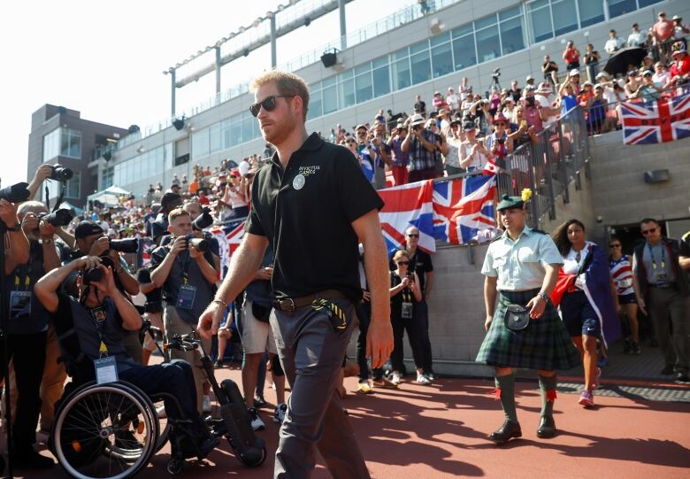 Britain's Prince Harry walks through a crowd at an athletic event. 