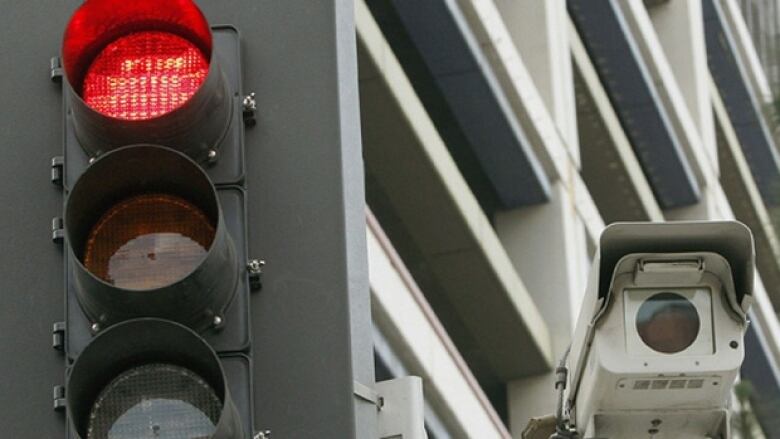 A camera is shown to the right of a set of traffic lights. 