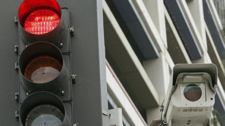 A camera is shown to the right of a set of traffic lights. 