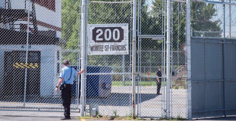 A guard stands outside gates of an immigration holding centre.