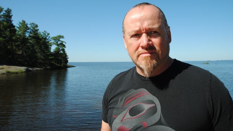 A man standing in front of a lake.