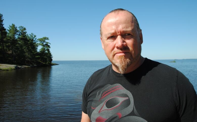 A man standing in front of a lake.