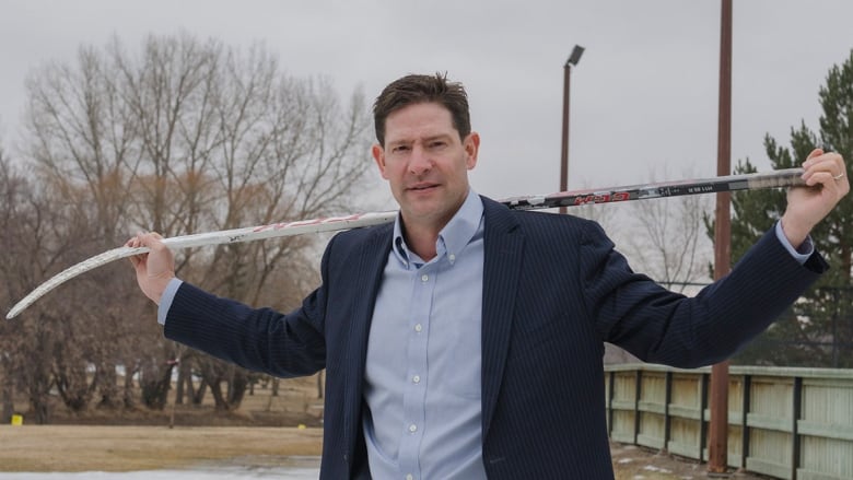 Trent McCleary poses with a hockey stick over his shoulders.