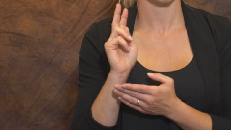 A woman signing in ASL with her two hands.