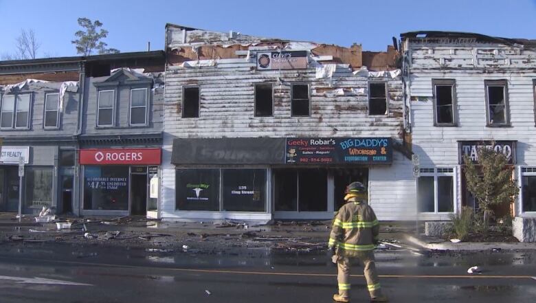 a block of buildings are charred and wet after a fire. 