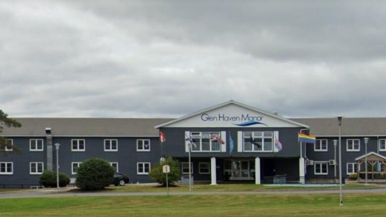 A building behind a green lawn with trees, lights and a sign for Glen Haven Manor.