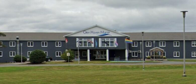 A building behind a green lawn with trees, lights and a sign for Glen Haven Manor.