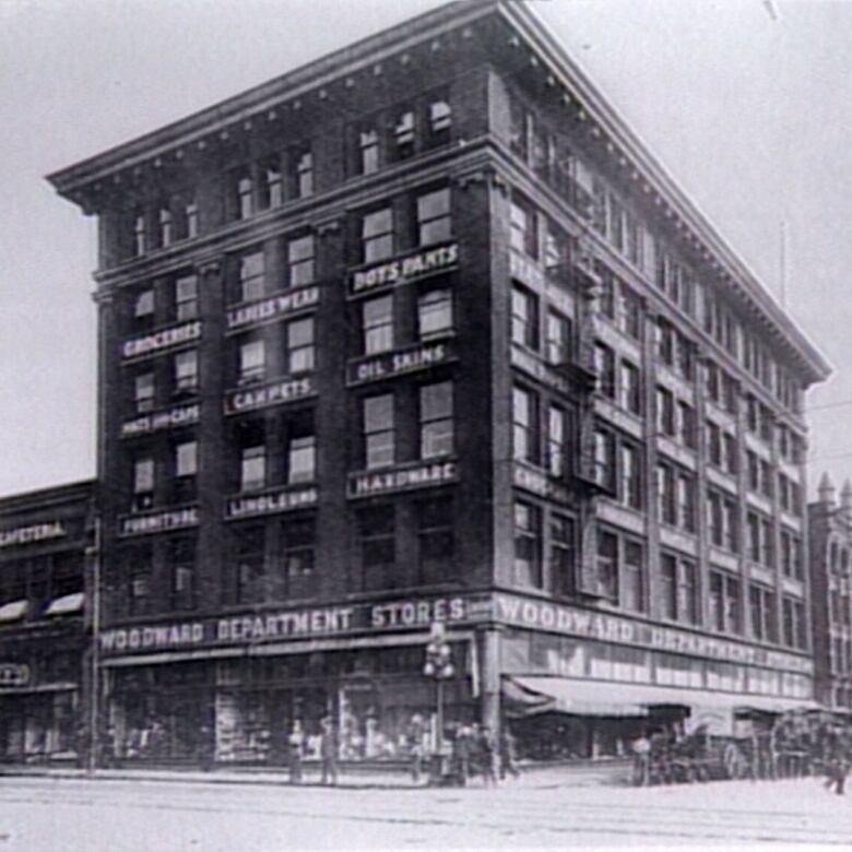 A black-and-white picture of a tall department store that reads 'Woodward Department Store'.