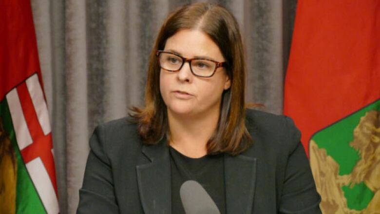 A woman with brown hair speaks before a microphone.