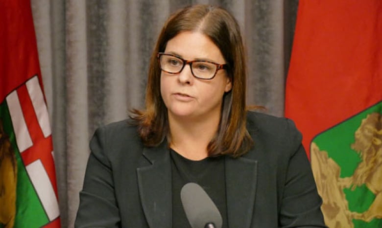 A woman with brown hair speaks before a microphone.