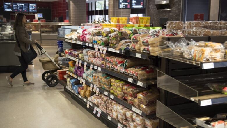 A woman shops the bakery aisle at a supermarket.