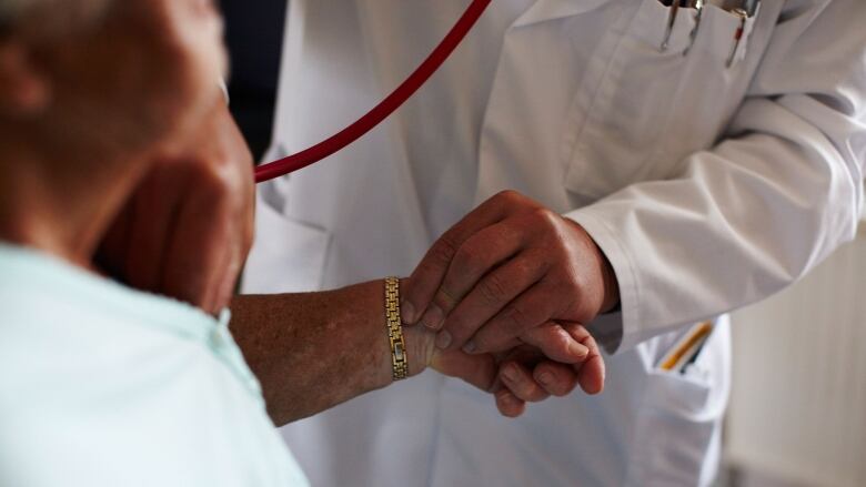 A doctor holding a patients hand.