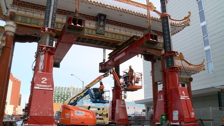 Construction workers dismantling a large structure decorated with Chinese symbols.