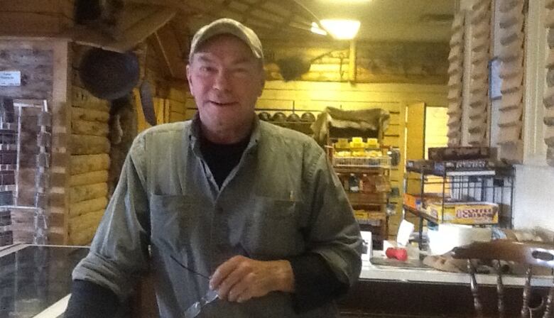 A man in a ball cap stands inside what looks like a snack bar.