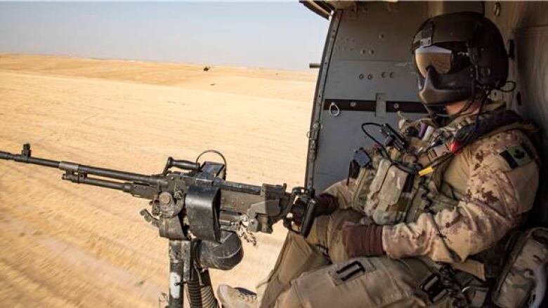 A door gunner with the tactical aviation detachment watches out of a CH-146 Griffon helicopter during Operation IMPACT on September 27, 2017.