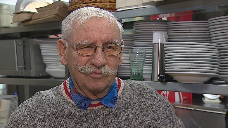 A close-up shot of a man in a grey sweater.