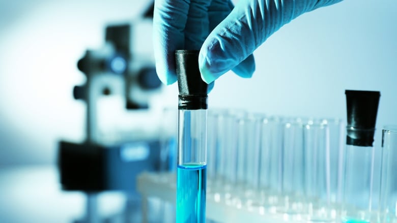 Pharmacist handling test tubes in a lab. 