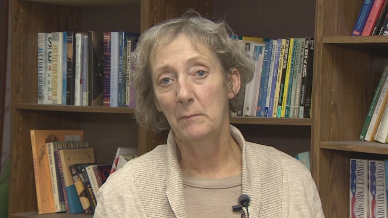 A woman in front of a book case. 