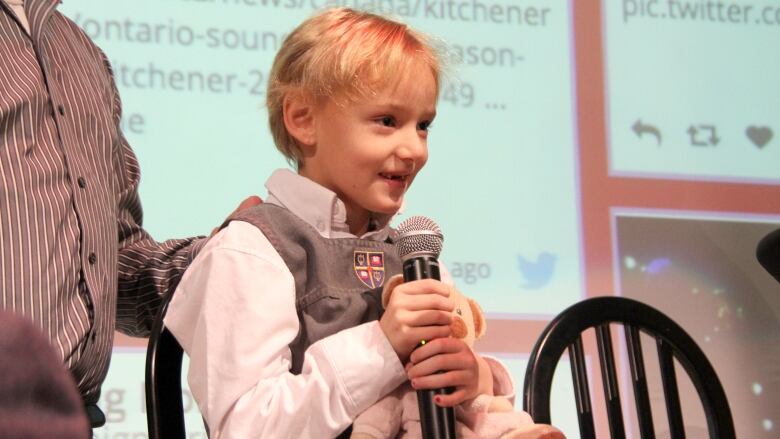 A young girl holds a CBC microphone and speaks during an interview