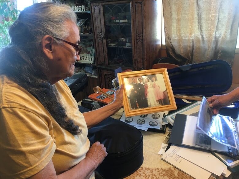 A woman holding a framed photo over a table in a home.