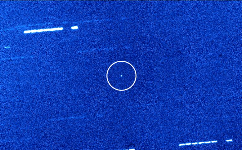 The grainy blue speckled image shows Oumuamua as a tiny white speck in the centre.