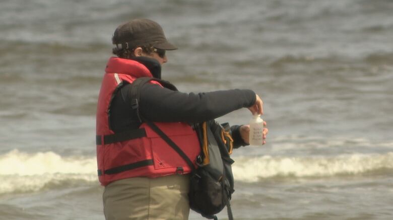 Woman taking sample of water at Parlee beach.