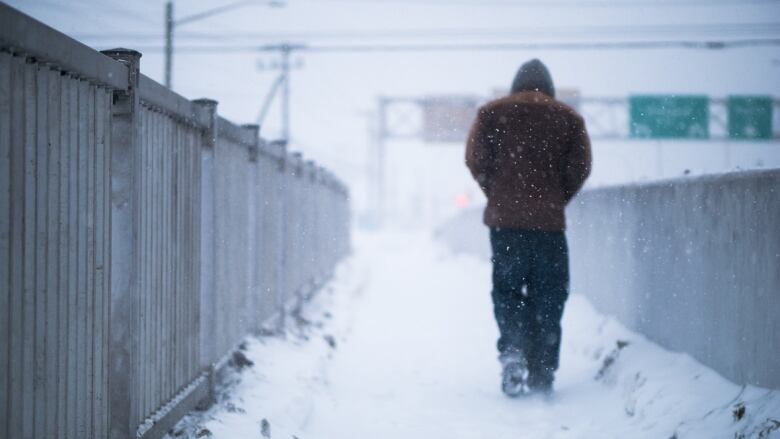 Person walking on a bridge in heavy winder conditions.