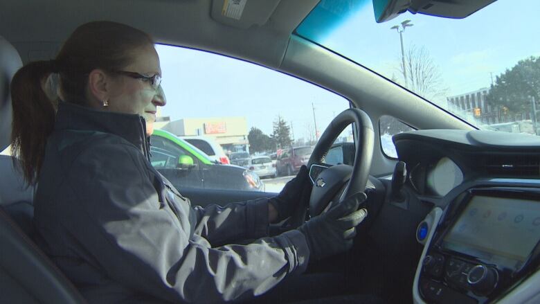 A woman sits behind the wheel of a car.