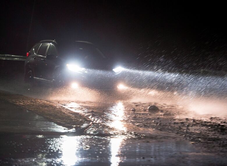 Car headlights are visible on a flooded road.